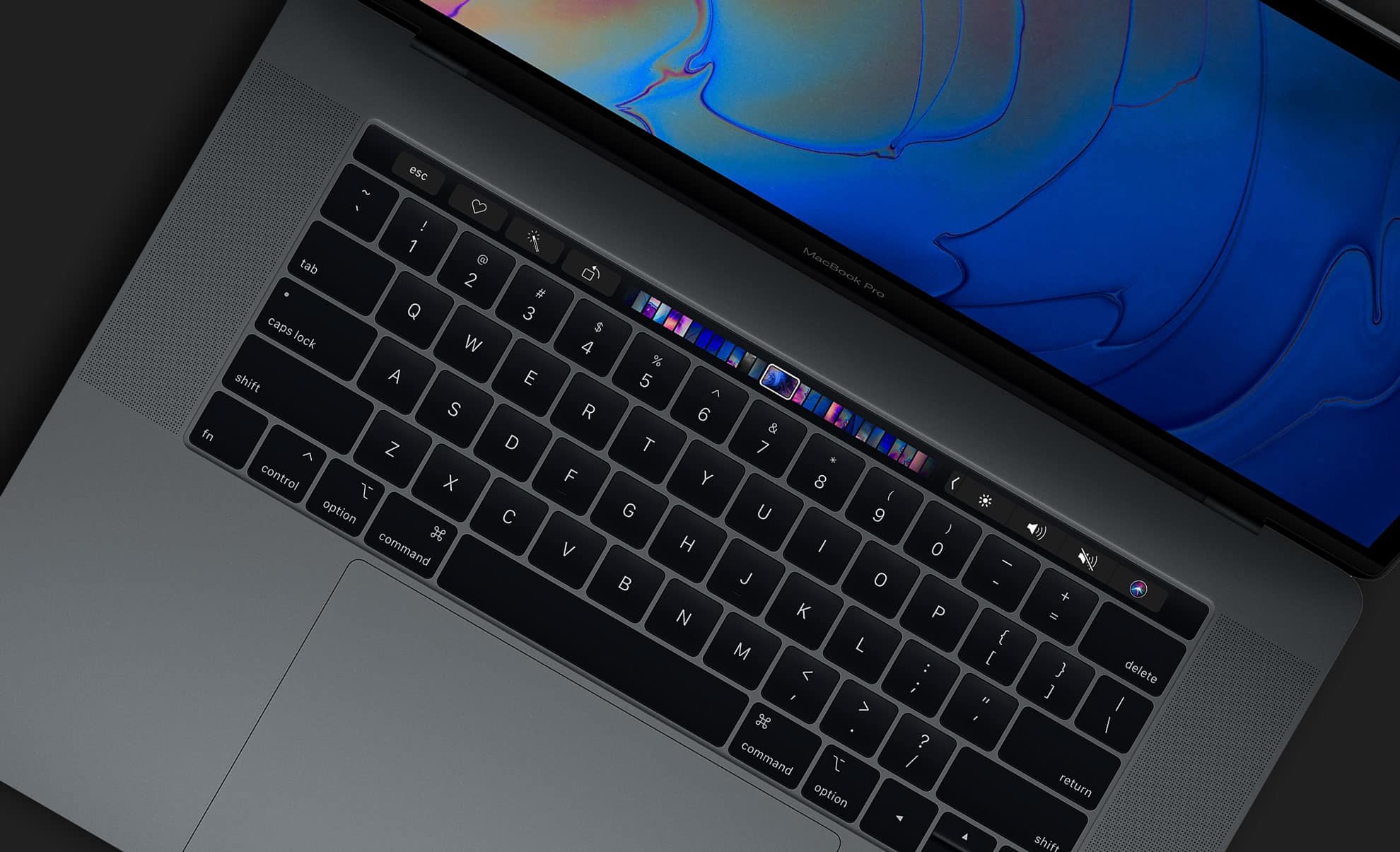 A close-up view of a MacBook keyboard, featuring a sleek black design with a touch-sensitive OLED bar above the keys. The screen displays a vibrant, abstract pattern in blue and purple colors. Part of the Apple Pro lineup, it includes standard keys and additional function keys.