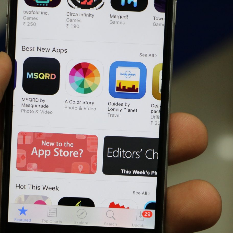 Close-up view of a smartphone screen displaying the Best New Apps section of the App Store. Visible apps include MSQRD, A Color Story, and Guides by Lonely Planet. Some app icons and a banner promoting the Apple App Store are also visible.