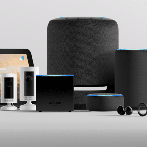 A collection of Amazon Alexa-enabled devices is arranged on a white surface. It includes smart speakers, a smart display showing the time (10:10) and weather, security cameras, AirPods, smart glasses, earbuds, a light switch, and a glowing orb-shaped light.