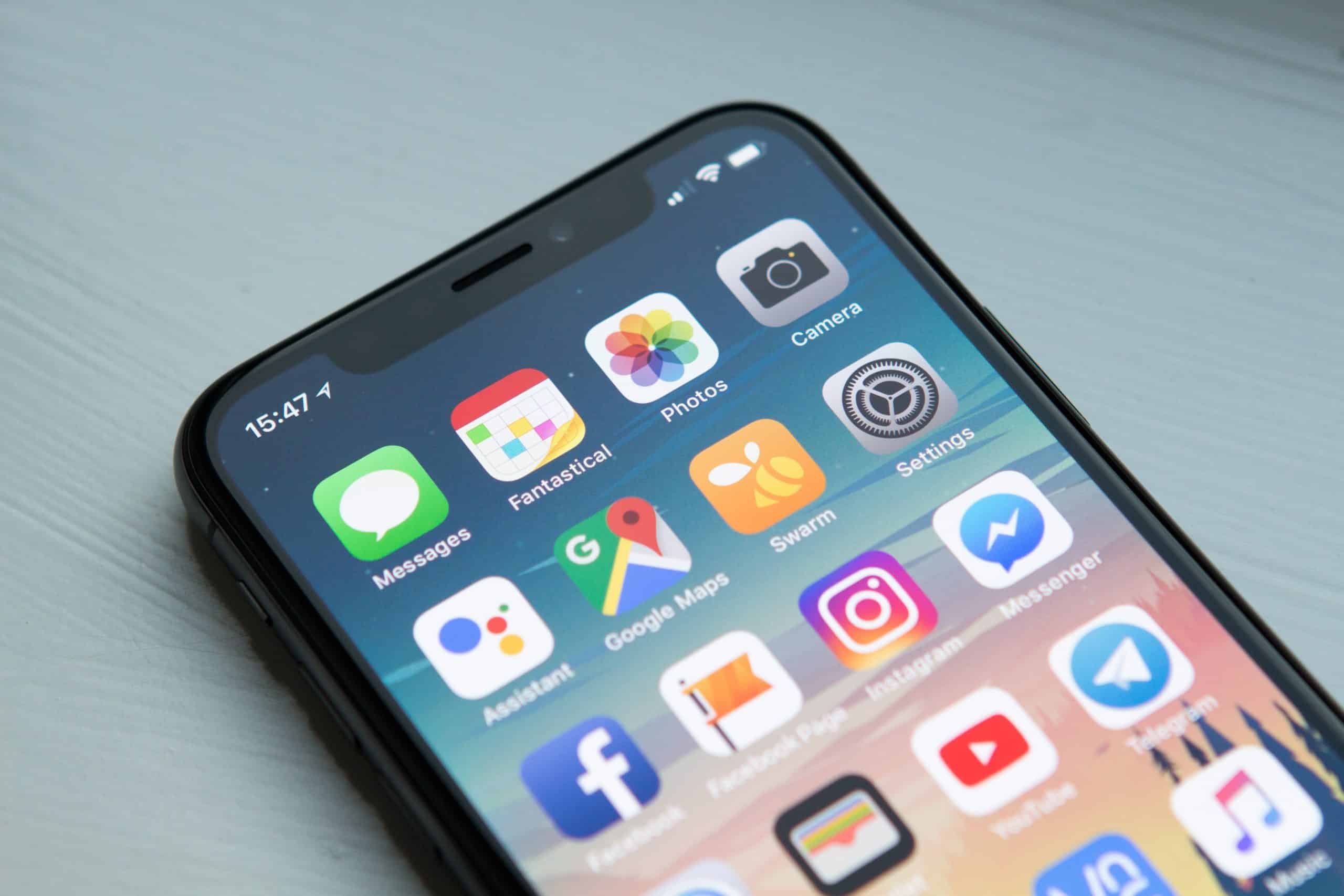 A smartphone displaying its home screen with various app icons including Messages, Fantastical, Photos, Camera, Assistant, Google Maps, Messenger (featuring the new Facebook Messenger redesign), Instagram, and Settings. The time shown is 15:47. The phone is placed on a light-colored surface.
