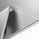 Close-up of the back of an Apple Studio Display, showcasing its silver finish with Mini-LED technology. The sleek, adjustable stand and part of the ventilation grille are visible at the bottom, while the metallic finish reflects light, emphasizing its modern design.
