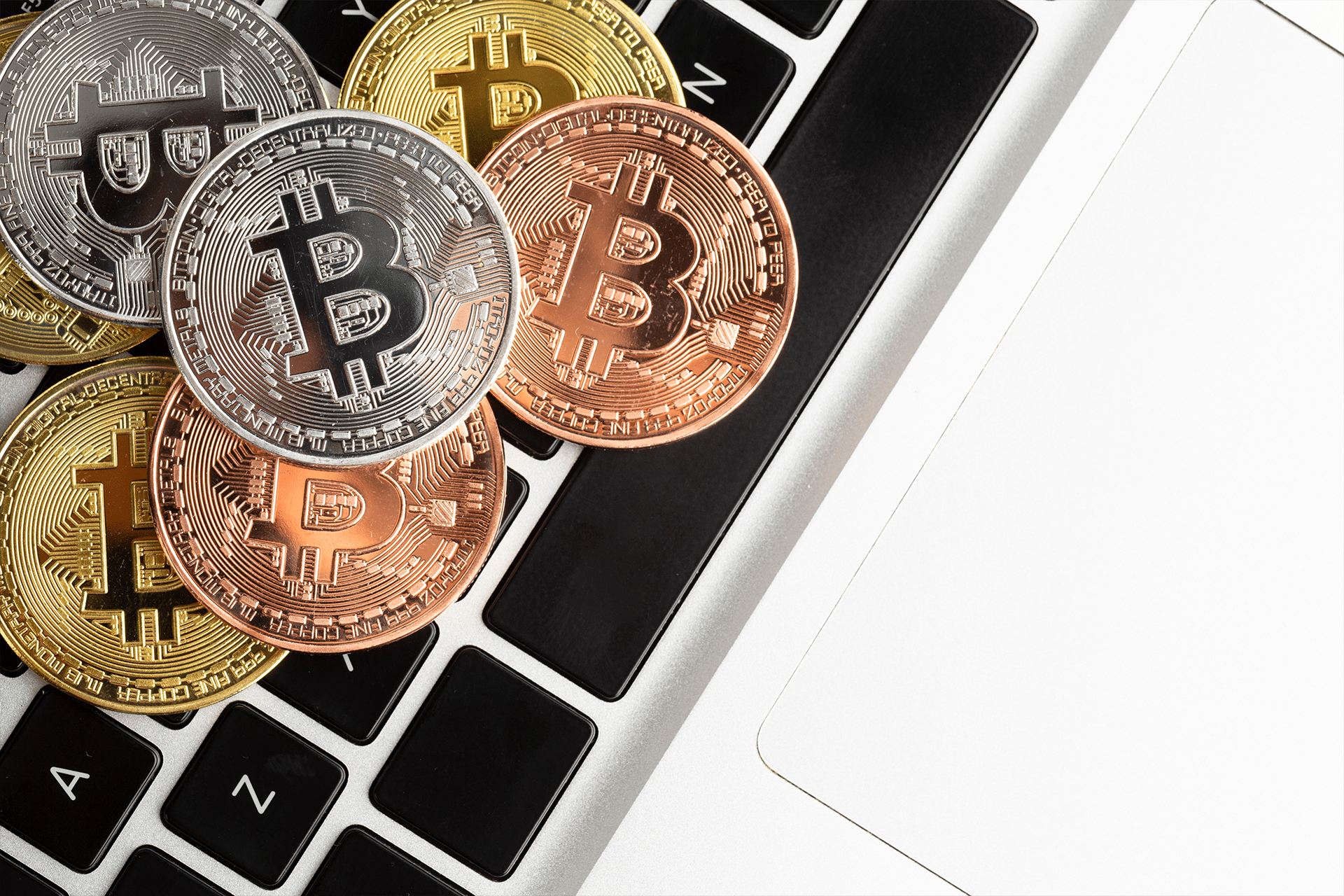 Several gold, silver, and bronze Bitcoin coins are placed on the black and white keyboard of a laptop, symbolizing digital currency and technology—a common scene among crypto startups often targeted by macOS malware.