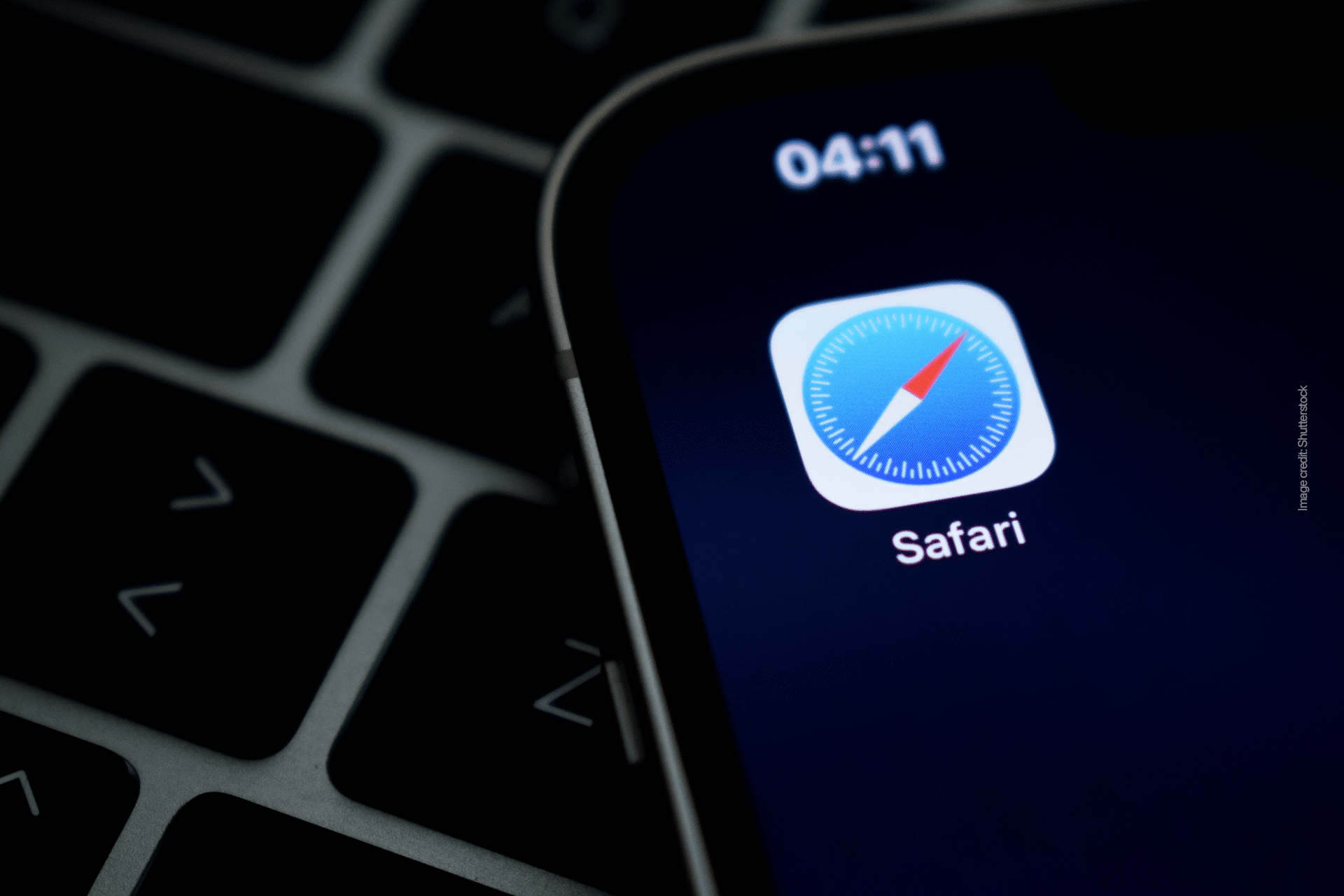Close-up of a smartphone displaying the Safari app icon on its screen, highlighting Apple’s commitment to a smarter web. Part of a keyboard is visible in the background, and the time at the top reads 04:11.