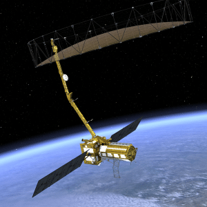 A gold-colored NISAR satellite with large solar panels and a wide radar antenna or reflector orbits above Earth against the dark backdrop of space.