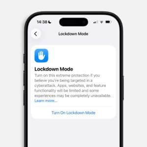 A smartphone screen displays the iPhone Lockdown settings page, describing an extreme protection mode for cyberattacks, with an option to "Turn On Lockdown Mode." The time on the phone is 14:38.