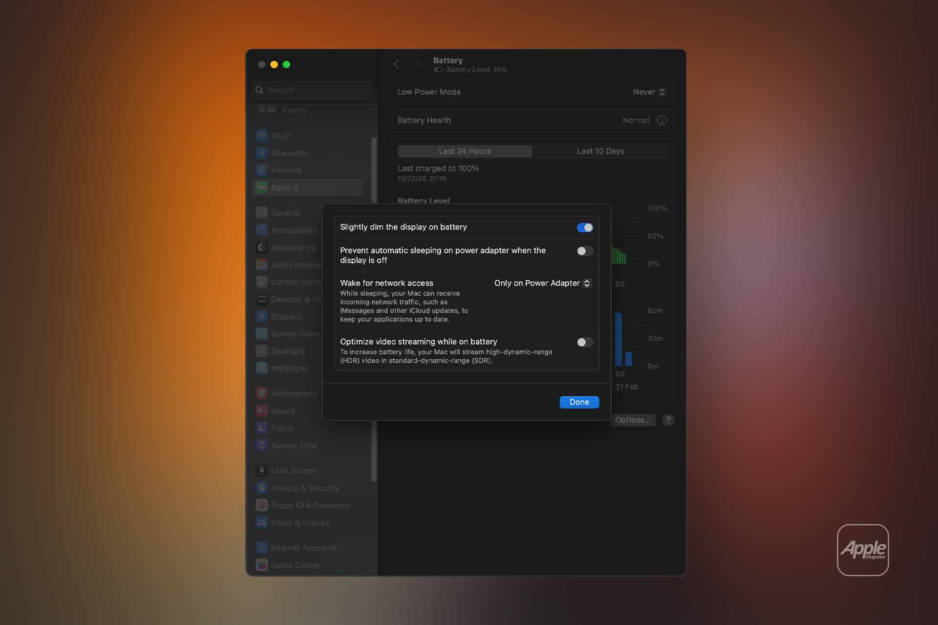 A MacBook screen displays the Battery settings window, with options to adjust display dimming and network access for optimal Mac performance. The background is blurred in warm tones, with a faint Apple logo in the corner.