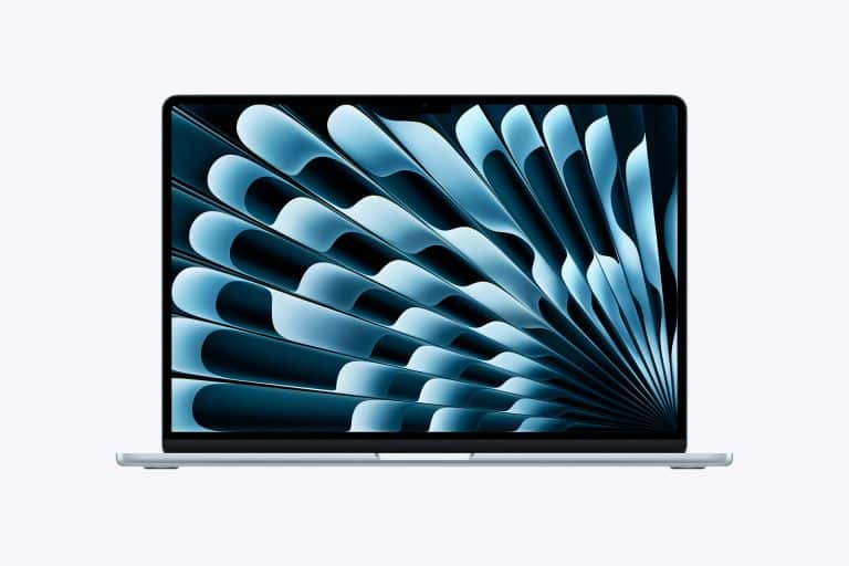 A silver M5 MacBook Air open on a white background displays a blue abstract geometric pattern on its screen. The design features layered, curved shapes radiating from the right side.