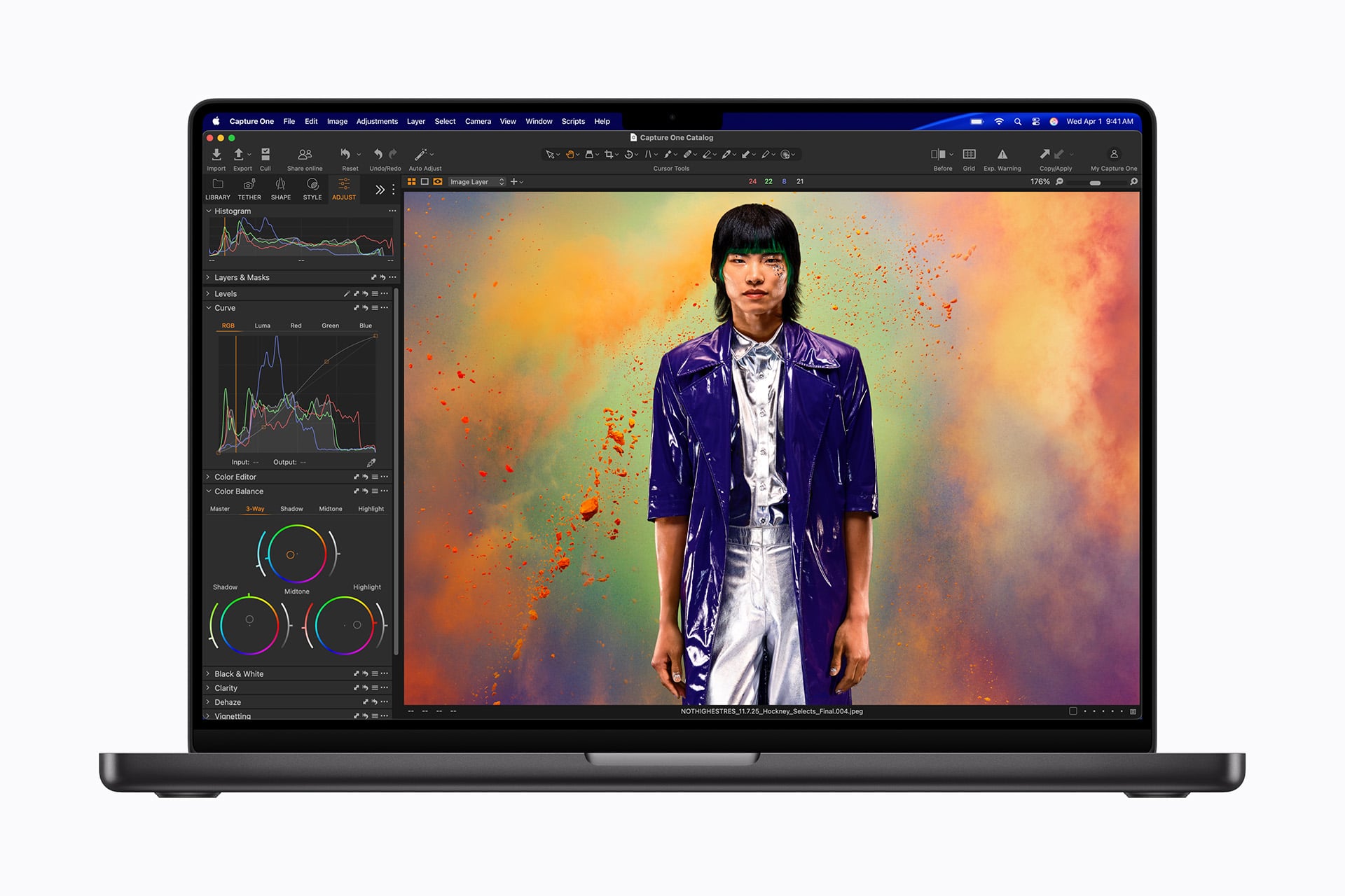 A laptop screen displays photo editing software with a colorful portrait of a person in a shiny purple jacket against a vibrant, multicolored background. Editing tools and adjustment panels are visible on the left side of the screen.