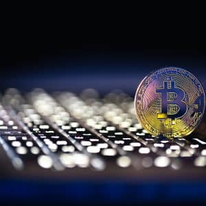 A physical Bitcoin stands upright on a laptop keyboard, illuminated by dramatic lighting, symbolizing digital currency and online transactions—while hinting at the growing threats such as macOS malware and crypto theft.