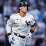 A New York Yankees baseball player in a pinstripe uniform and helmet runs on the field during a game, with a blurred crowd in the background—a scene that feels even more immersive when experienced through Apple Vision Pro’s 3D MLB games during Friday Night Baseball.