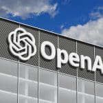 A modern building with the OpenAI logo and name on its facade, set against a partly cloudy blue sky, evokes the spirit of innovation at the heart of recent developments such as the OpenAI motion in the ongoing Apple lawsuit.